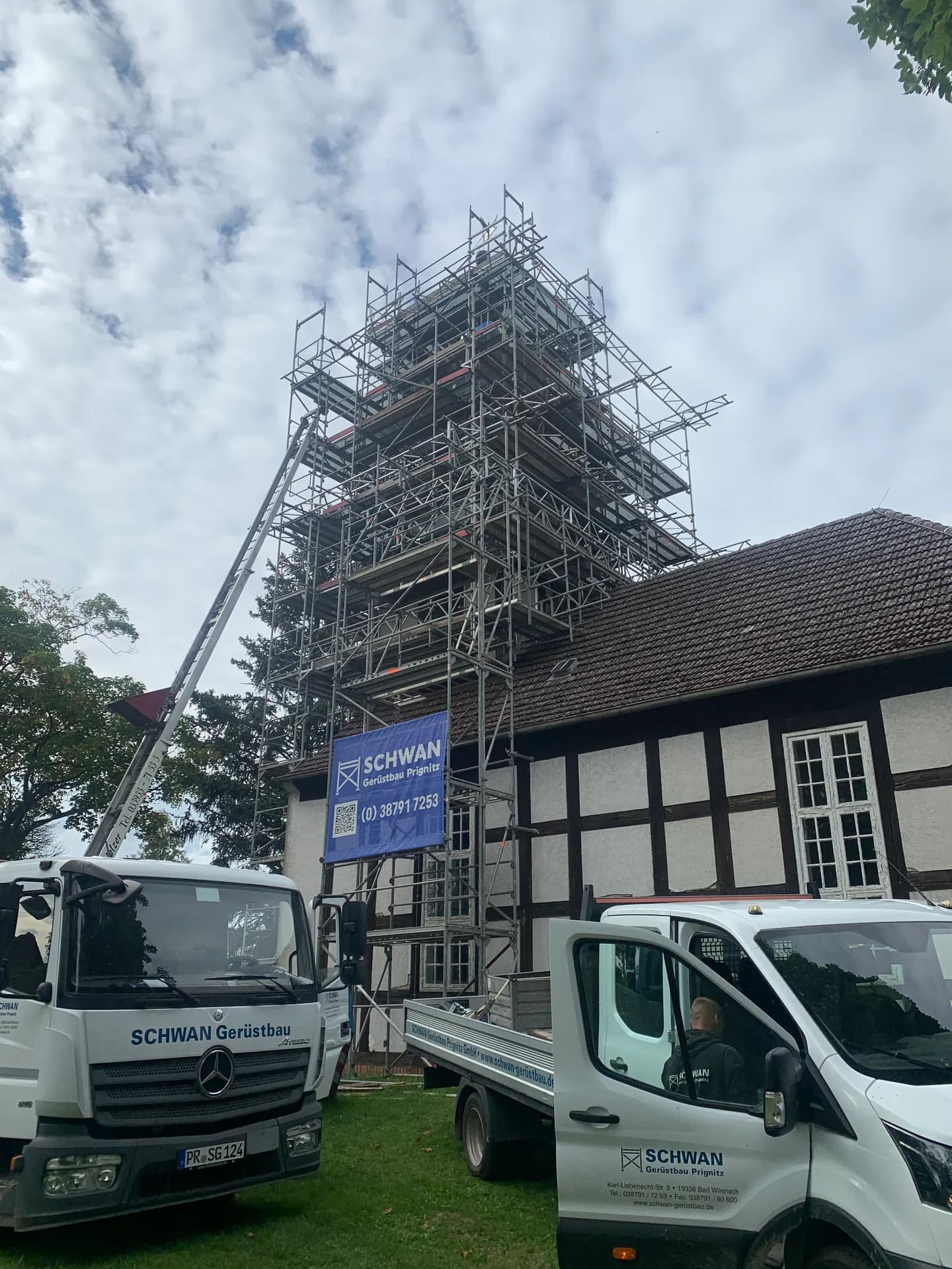 SCHWAN-Gerüstbau-Fahrzeuge und Schrägaufzug vor der eingerüsteten Kirche Braunsberg