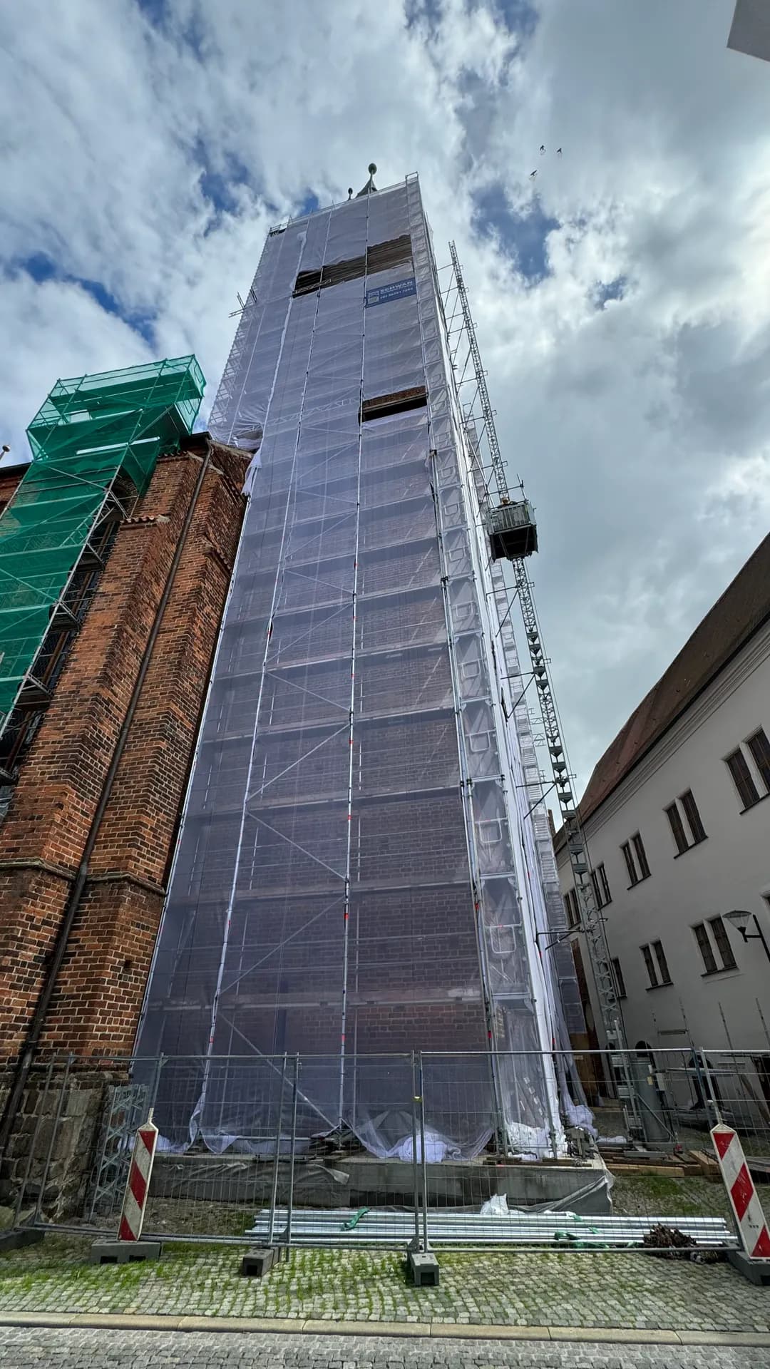 Eingerüsteter und abgenetzter Kirchturm der Marienkirche Stendal mit Geda-500-Aufzug, SCHWAN Gerüstbau